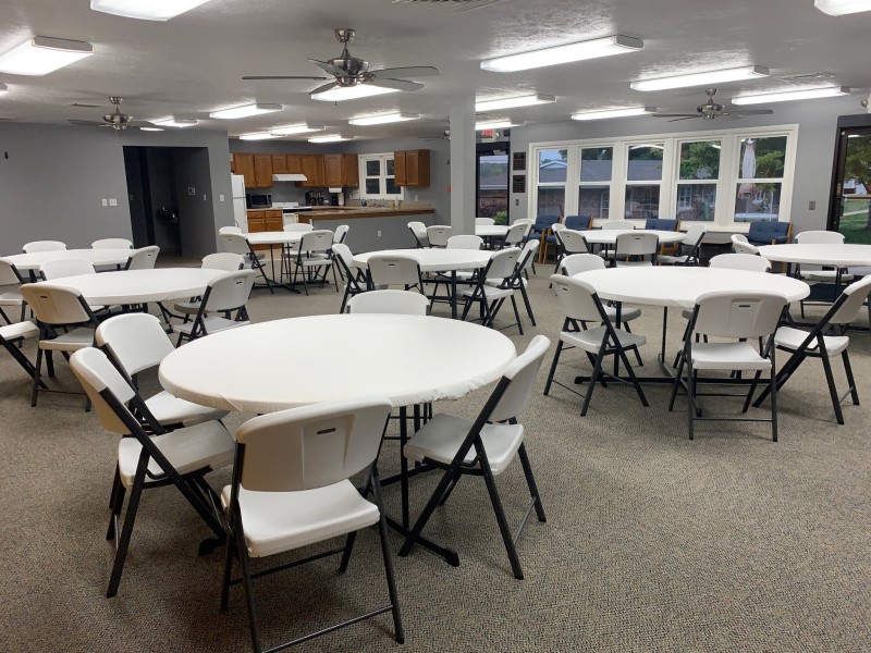 Picture of the new tables and chairs set up in the Community Room with the kitchen in the background